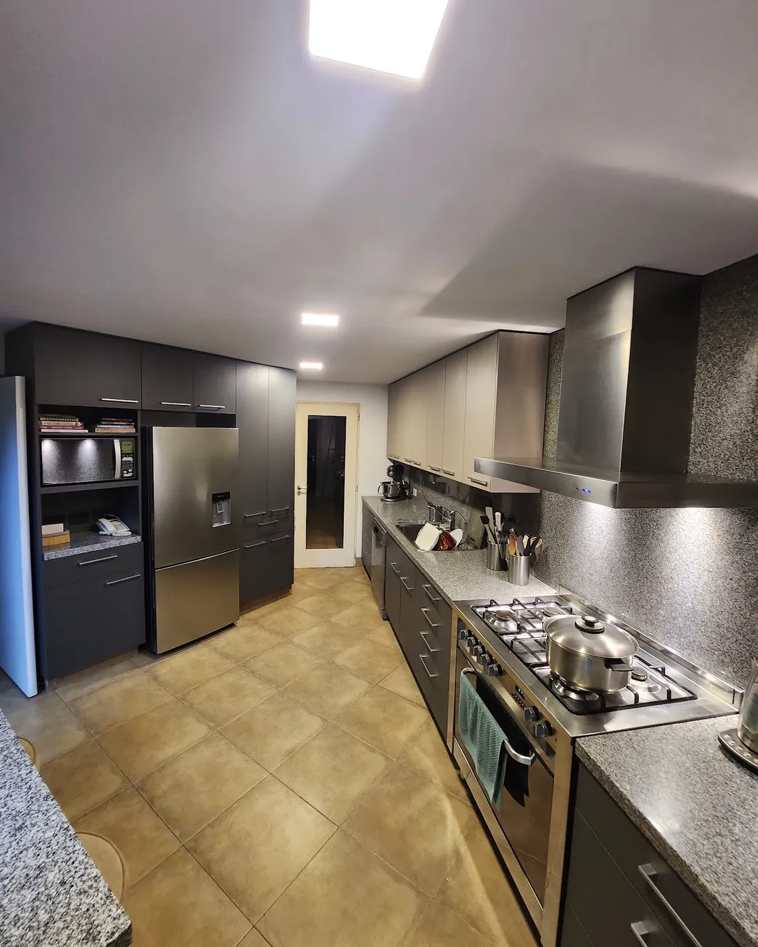 Cocina a medida en gris grafito y negro, con columnas para horno y heladera, hecha por Carpintería DYM