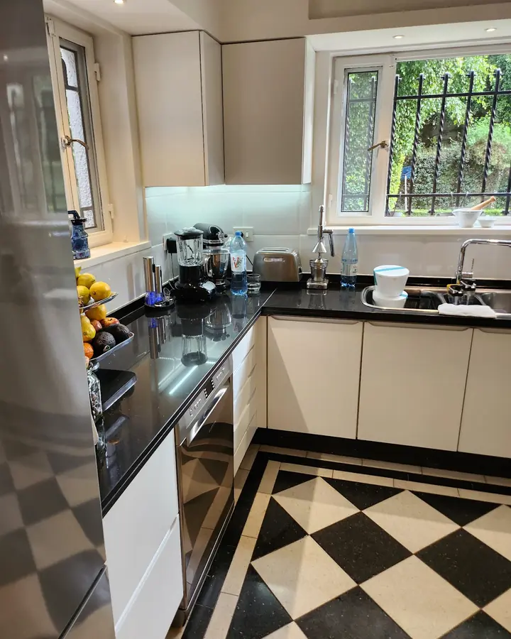 Cocina blanca con mesada negra y piso damero